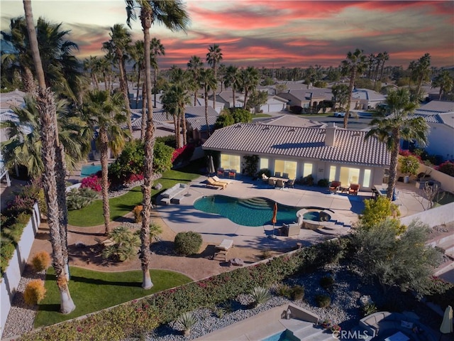 pool at dusk with an in ground hot tub and a patio