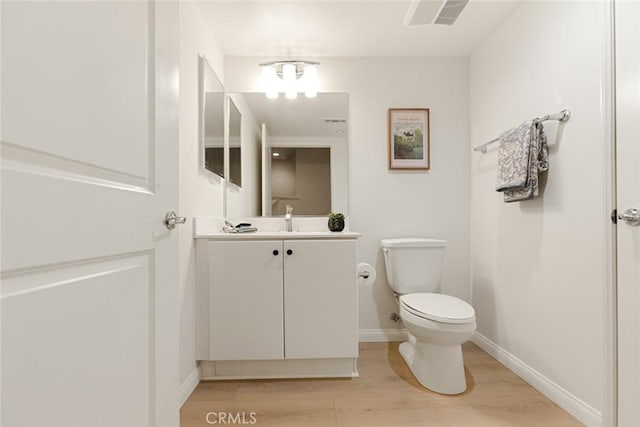 bathroom with toilet, hardwood / wood-style floors, and vanity