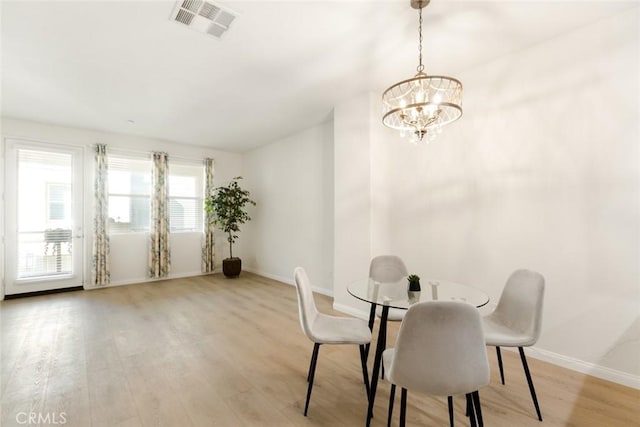 dining area with a notable chandelier and light hardwood / wood-style flooring