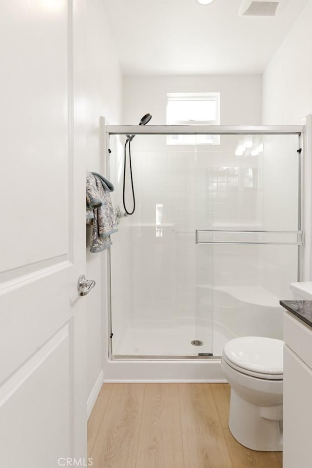 bathroom with walk in shower, toilet, vanity, and hardwood / wood-style flooring