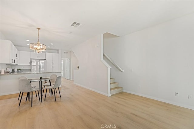 kitchen featuring white fridge, white cabinetry, pendant lighting, light hardwood / wood-style flooring, and an inviting chandelier