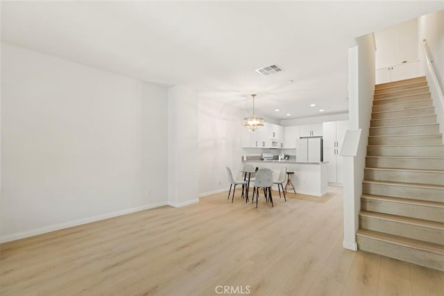 dining space with a notable chandelier and light hardwood / wood-style floors