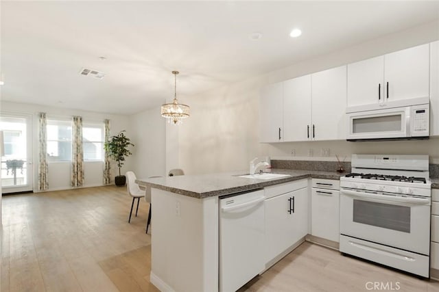 kitchen featuring white appliances, light hardwood / wood-style floors, kitchen peninsula, white cabinetry, and decorative light fixtures