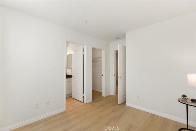 unfurnished bedroom with light wood-type flooring, a closet, and a spacious closet