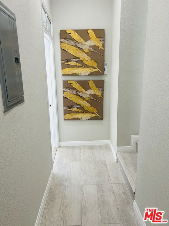 hallway with electric panel and light hardwood / wood-style flooring