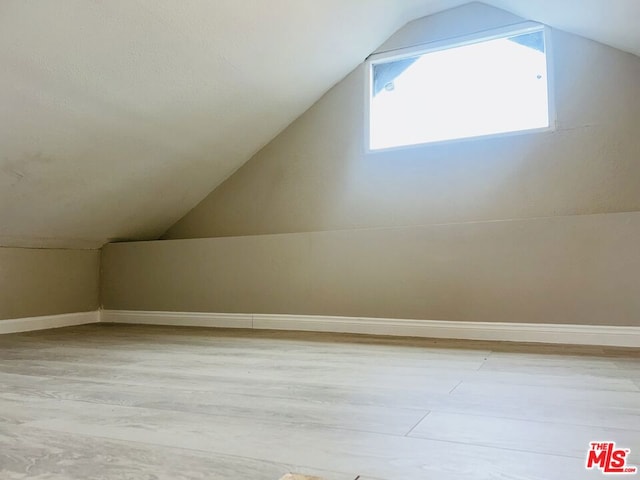 additional living space featuring vaulted ceiling and light hardwood / wood-style floors