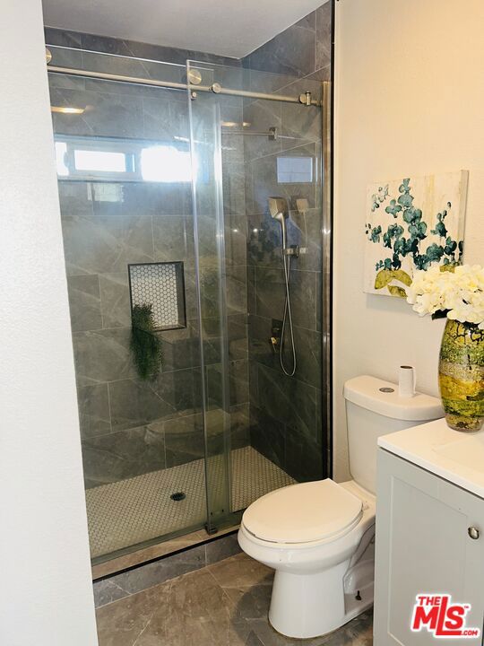 bathroom featuring toilet, an enclosed shower, and vanity