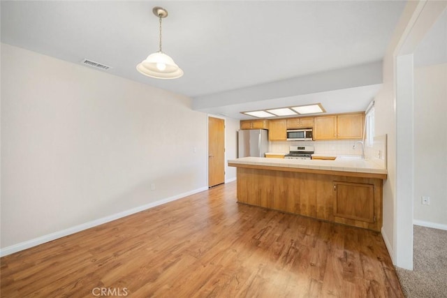 kitchen with sink, tasteful backsplash, light hardwood / wood-style flooring, kitchen peninsula, and appliances with stainless steel finishes