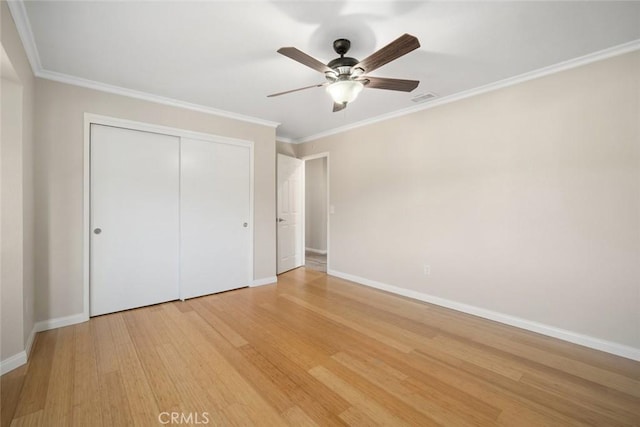 unfurnished bedroom featuring ceiling fan, crown molding, a closet, and light hardwood / wood-style flooring