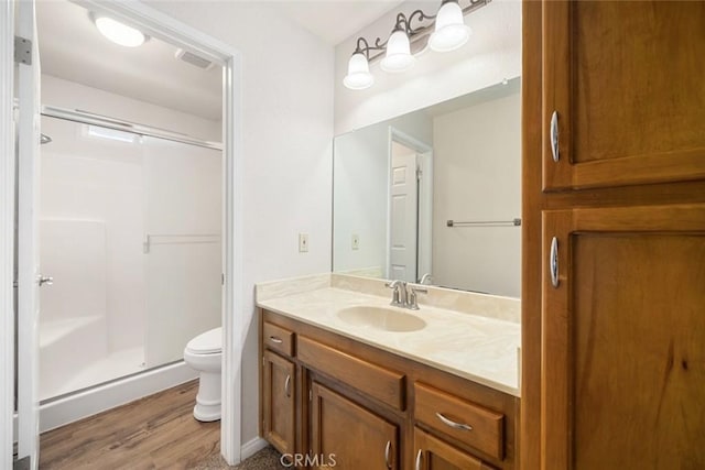 bathroom featuring toilet, hardwood / wood-style flooring, walk in shower, and vanity