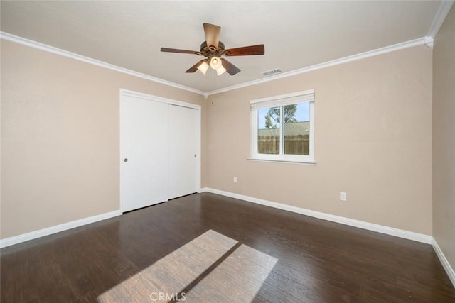 unfurnished bedroom with a closet, ceiling fan, crown molding, and dark hardwood / wood-style floors