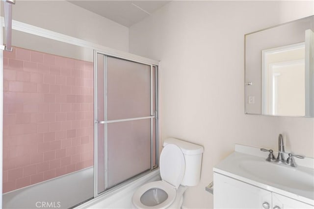 full bathroom featuring combined bath / shower with glass door, vanity, and toilet