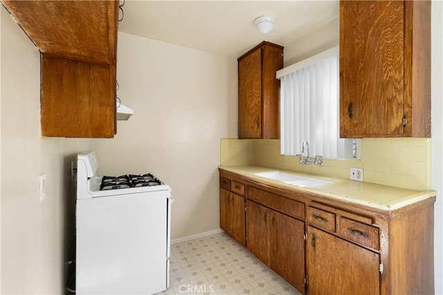 kitchen featuring sink, range hood, tasteful backsplash, and white gas range oven