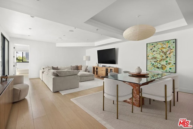 dining room with light hardwood / wood-style flooring and a raised ceiling