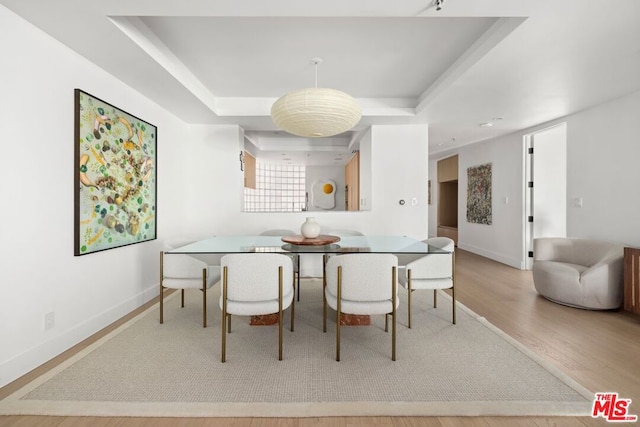 dining space featuring a tray ceiling and light hardwood / wood-style flooring