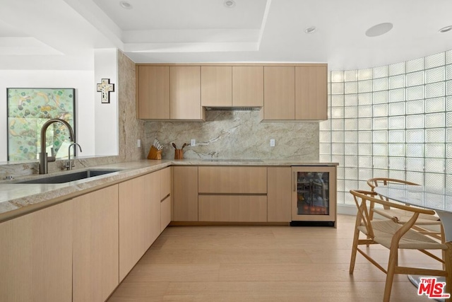 kitchen featuring sink, light brown cabinets, a raised ceiling, beverage cooler, and decorative backsplash