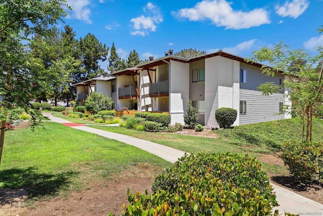 view of side of home featuring a balcony and a lawn