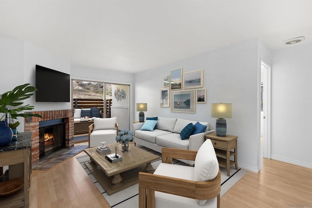 living room featuring light wood-type flooring and a brick fireplace