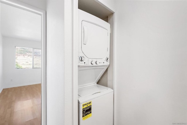 washroom with hardwood / wood-style floors and stacked washer / drying machine