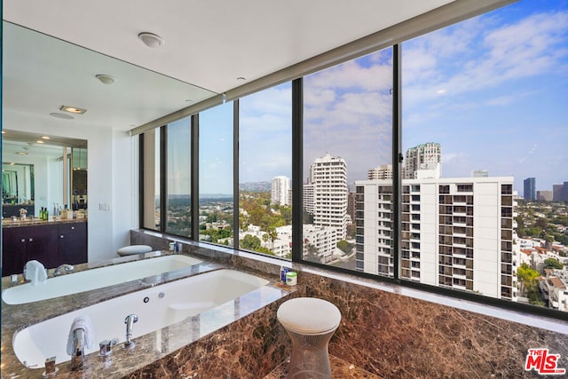 bathroom with vanity, expansive windows, a wealth of natural light, and tiled bath