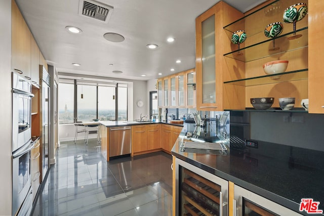 kitchen featuring beverage cooler, appliances with stainless steel finishes, kitchen peninsula, dark tile patterned flooring, and sink