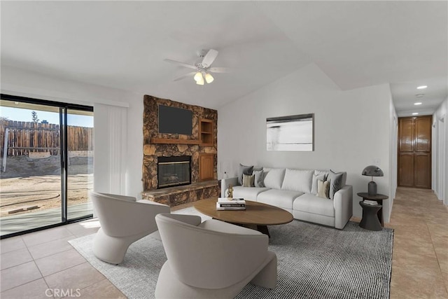 tiled living room with ceiling fan, lofted ceiling, and a fireplace