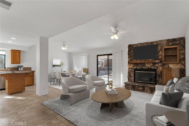 living room with light tile patterned flooring, ceiling fan, and a stone fireplace