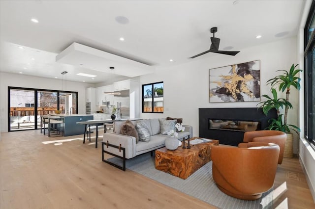 living room featuring ceiling fan, light hardwood / wood-style flooring, and a healthy amount of sunlight