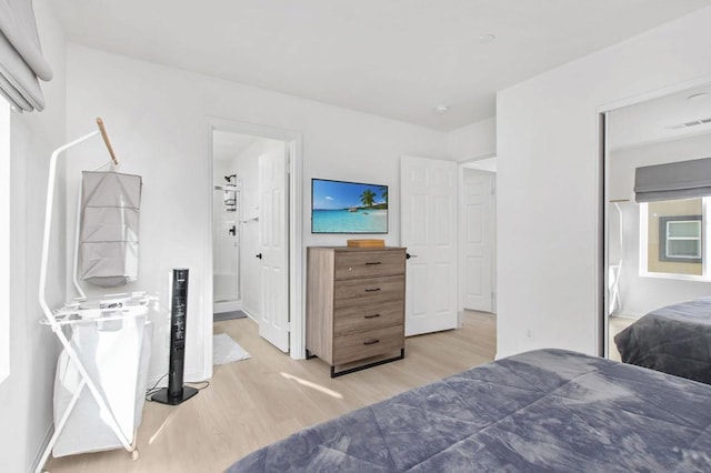 bedroom with light wood-type flooring and ensuite bath