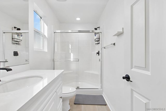 bathroom with toilet, an enclosed shower, vanity, and hardwood / wood-style flooring