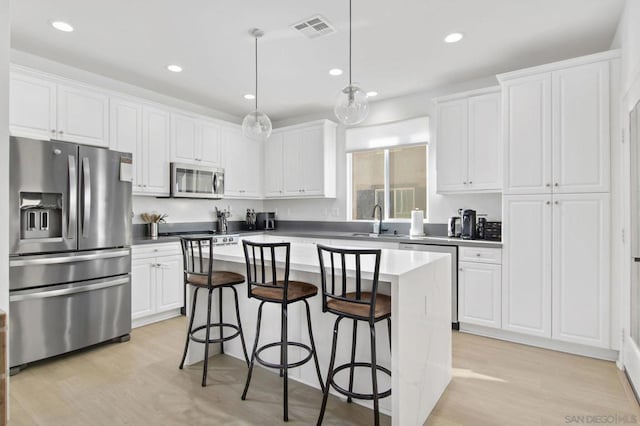 kitchen with stainless steel appliances, white cabinetry, and a center island