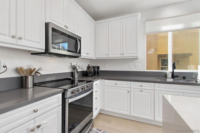 kitchen featuring stainless steel appliances, plenty of natural light, sink, light hardwood / wood-style flooring, and white cabinetry