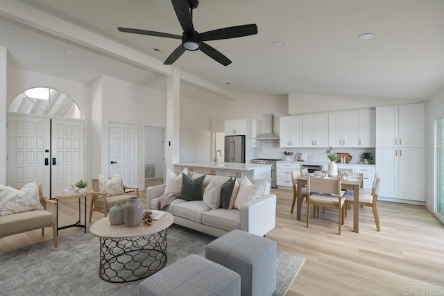 living room featuring ceiling fan, light hardwood / wood-style floors, high vaulted ceiling, and sink