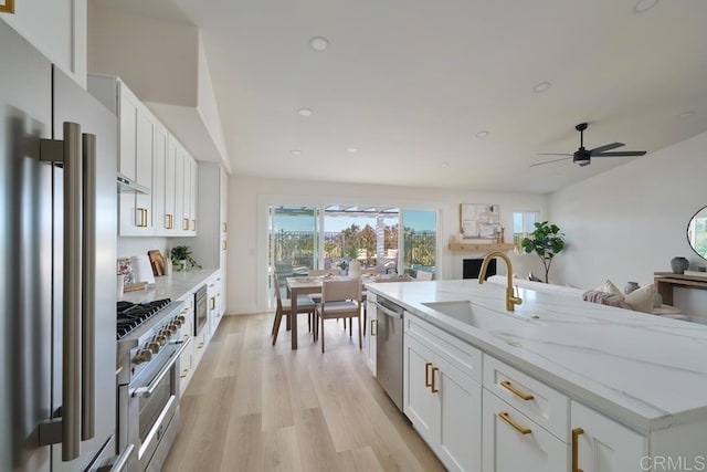 kitchen featuring ceiling fan, sink, stainless steel appliances, white cabinets, and light stone counters