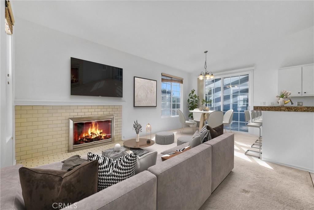 living room featuring light colored carpet, a brick fireplace, and an inviting chandelier