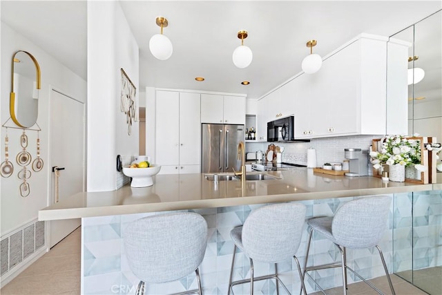 kitchen with kitchen peninsula, decorative light fixtures, white cabinetry, high end fridge, and sink