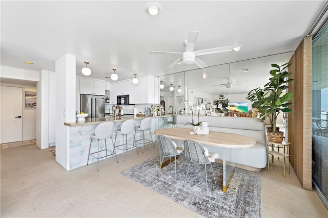 tiled dining room with ceiling fan and sink