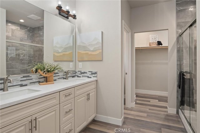 bathroom with a shower with door, backsplash, and vanity