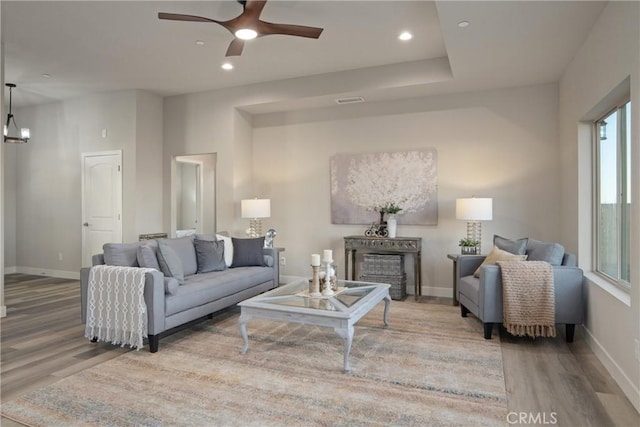 living room featuring light hardwood / wood-style floors, ceiling fan with notable chandelier, and plenty of natural light