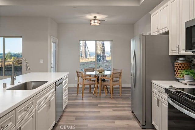 kitchen featuring sink, white cabinets, light hardwood / wood-style floors, backsplash, and appliances with stainless steel finishes