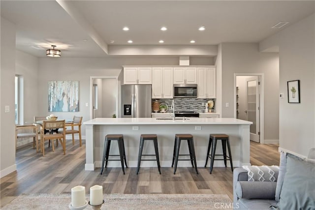 kitchen with white cabinets, stainless steel appliances, a breakfast bar area, and a spacious island