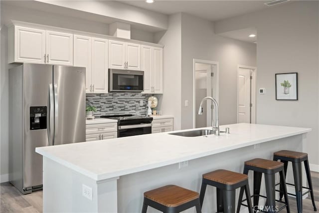 kitchen featuring sink, white cabinetry, an island with sink, and appliances with stainless steel finishes