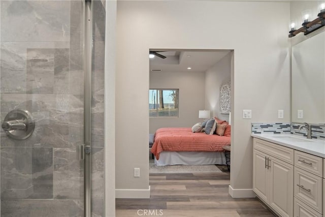 bathroom featuring ceiling fan, hardwood / wood-style flooring, decorative backsplash, an enclosed shower, and vanity