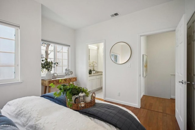 bedroom with hardwood / wood-style flooring and ensuite bath