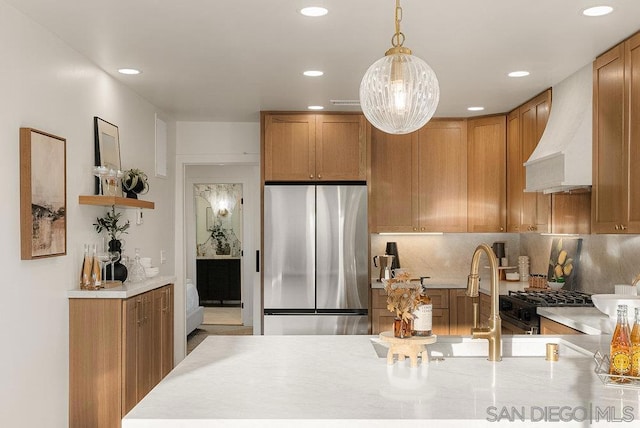 kitchen with tasteful backsplash, pendant lighting, stainless steel refrigerator, custom range hood, and range