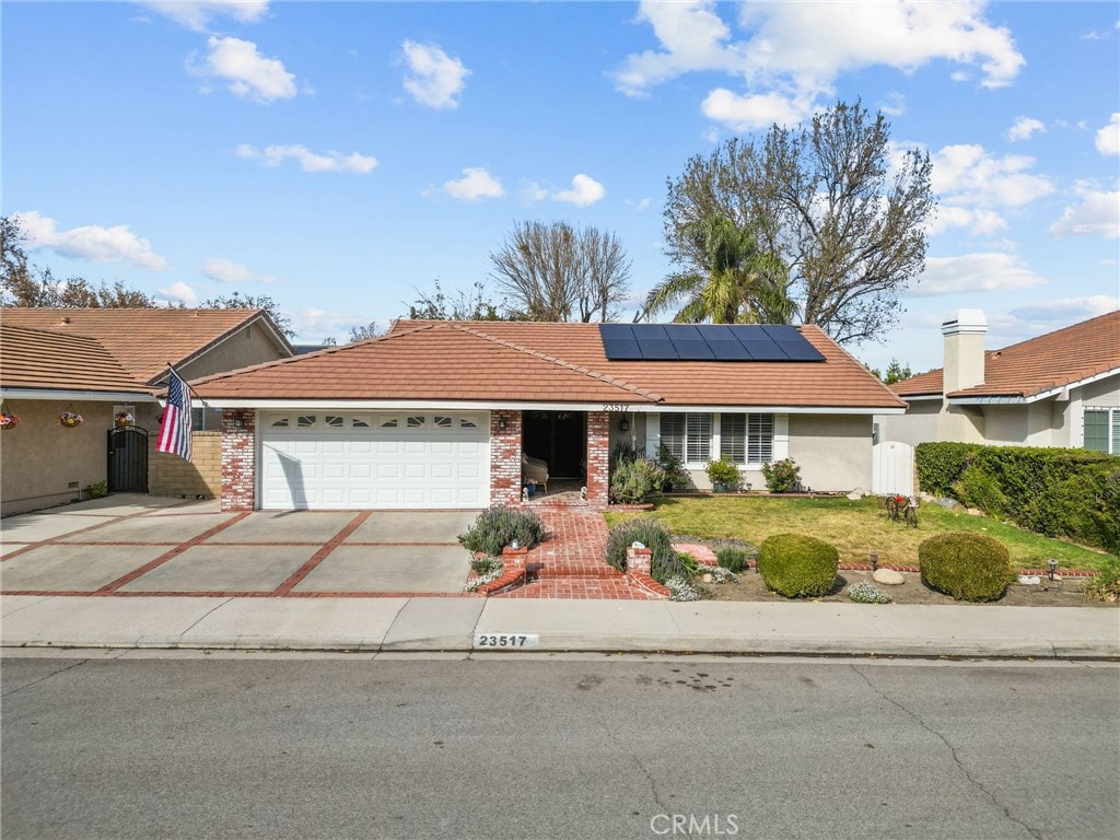 ranch-style house featuring solar panels, a front lawn, and a garage