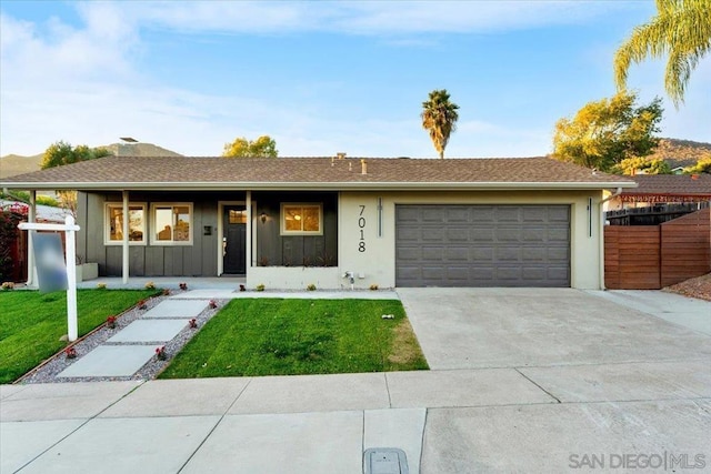 ranch-style house featuring covered porch, a front lawn, and a garage