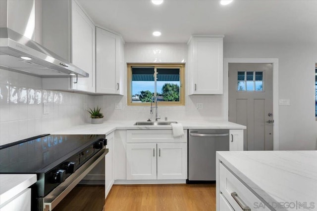 kitchen with stainless steel dishwasher, wall chimney exhaust hood, black range with electric cooktop, and white cabinetry