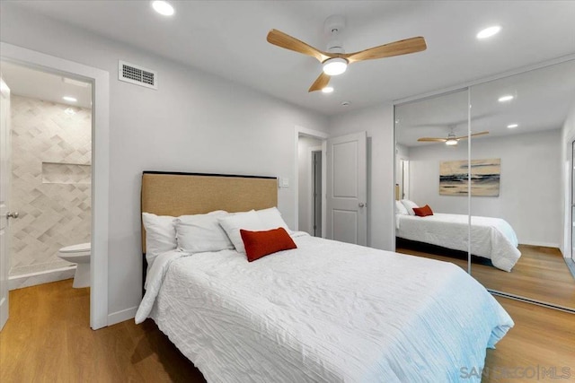 bedroom featuring ceiling fan, hardwood / wood-style floors, ensuite bathroom, and a closet