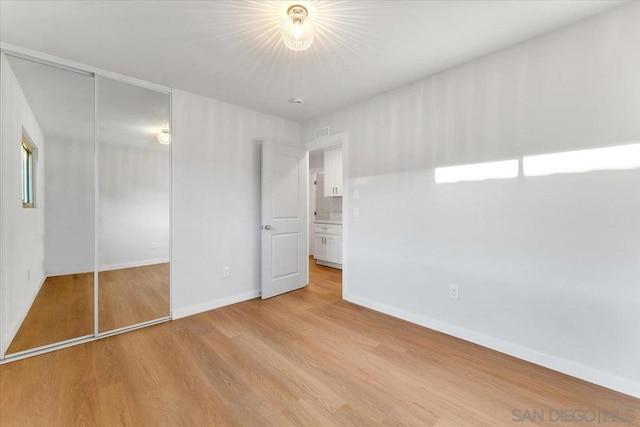 unfurnished bedroom with light wood-type flooring and a closet